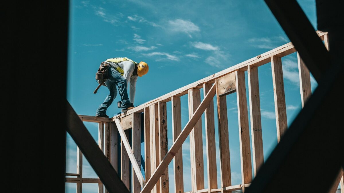 man in yellow shirt and blue denim jeans jumping on brown wooden railings under blue and