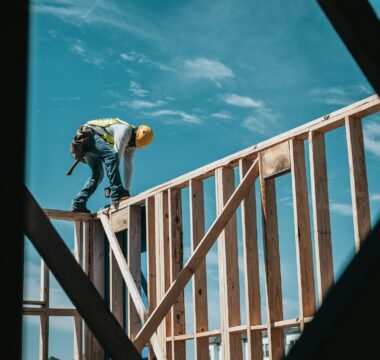 man in yellow shirt and blue denim jeans jumping on brown wooden railings under blue and